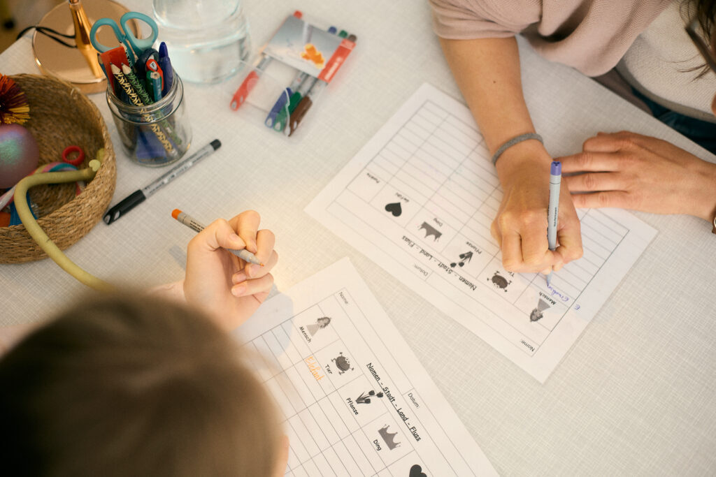 Kind und Lerntrainerin spielen ein Legastheniespiel am Tisch, Lerntraining Legasthenie