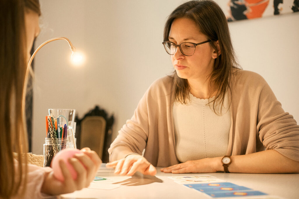 Lerntrainerin und Kind spielen ein Lernspiel am Tisch